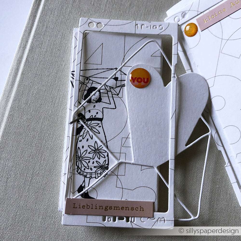 Eine handgefertigte Karte von Alexandra Renke mit abstrakten Motiven, einer Herzform und Anhängern mit YOU und Lieblingsmensch, hergestellt mit Deep Edge Motivstanzen für atemberaubende Details.