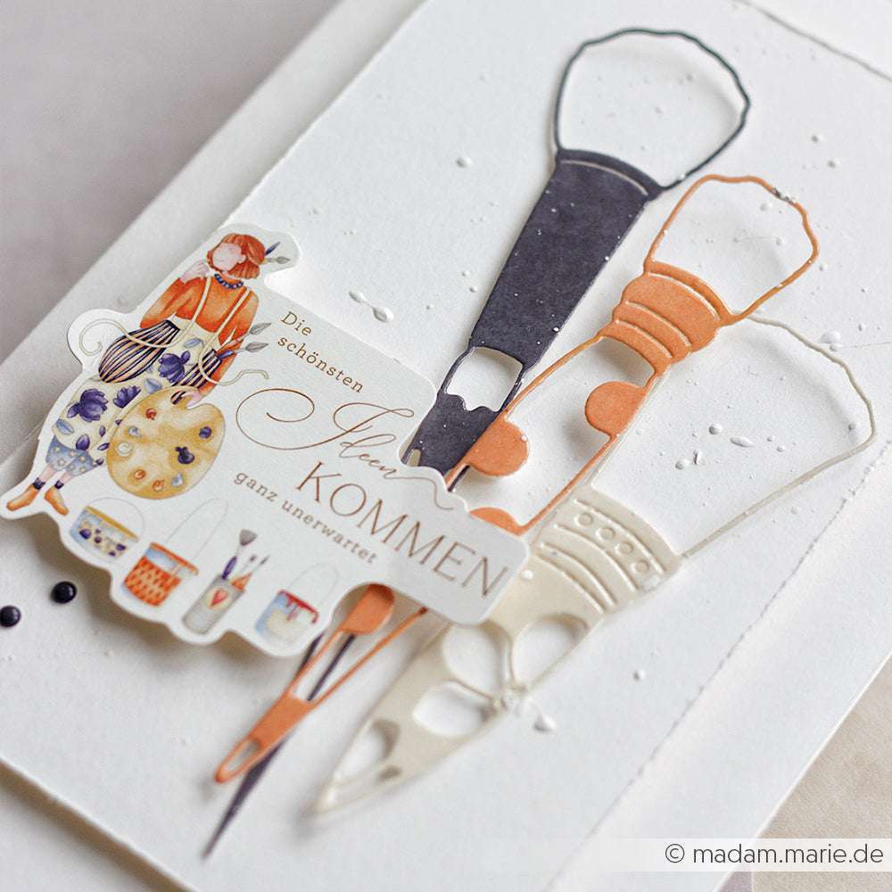 Eine Grußkarte von Alexandra Renke mit illustriertem Kunstzubehör und deutschem Text auf strukturiertem Weiß, akzentuiert mit Deep Edge Motivstanzen und einem PAPPcut Outline Pinsel.