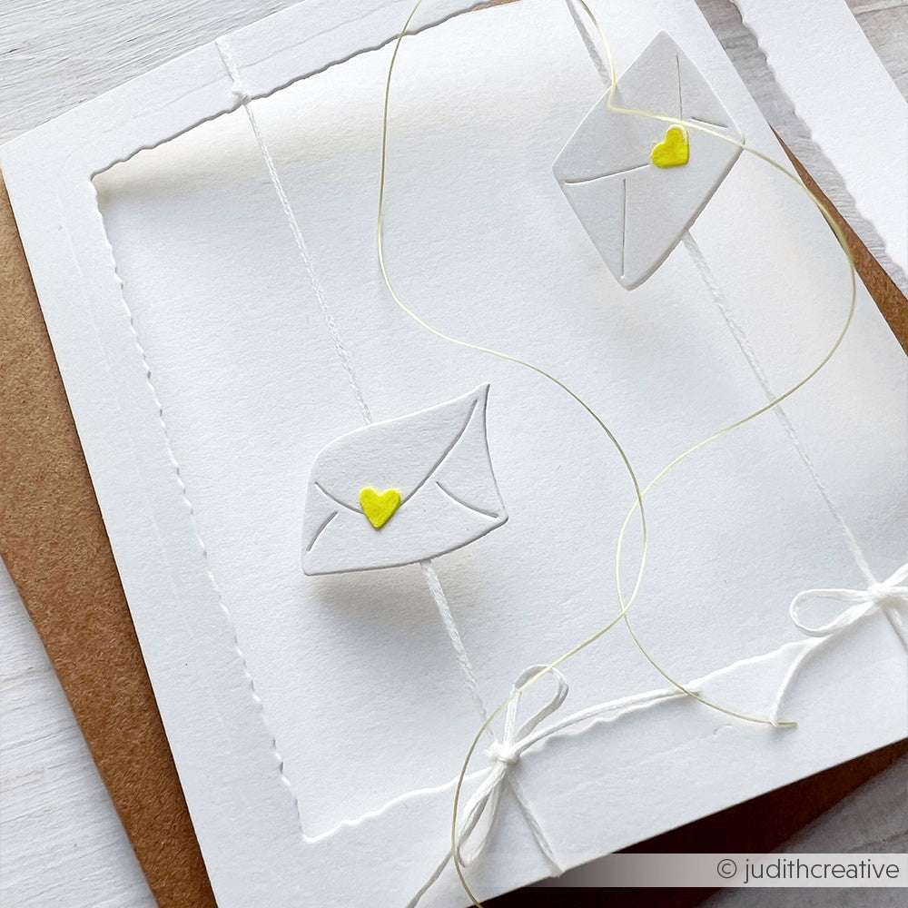 Handgefertigte Karte von Alexandra Renke mit zwei kleinen Umschlägen, die mit gelben Herzen und weißen Schleifen auf weißem Papier verschlossen sind, hergestellt mit Deep Edge Motivstanzen für gestochen scharfe Designs.