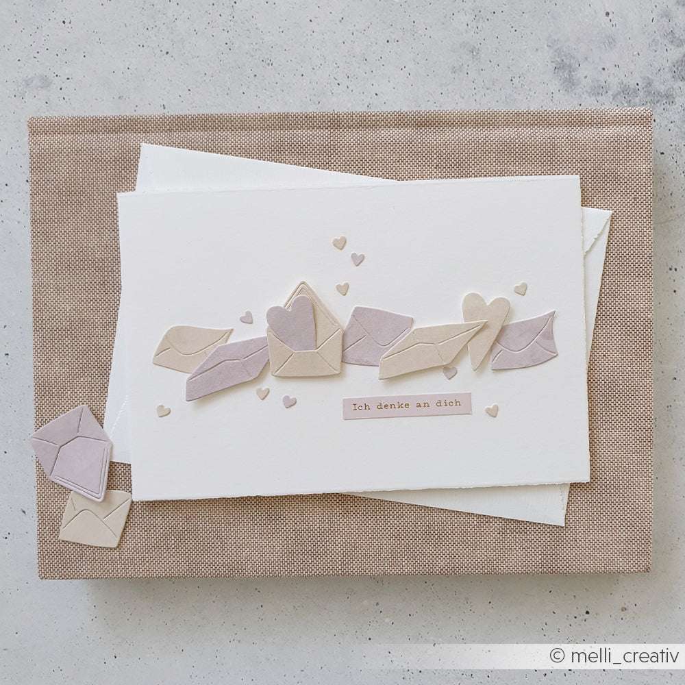Handgemachte Karte mit Papierumschlägen und Herzen auf weißem Papier, hergestellt mit dem Alexandra Renke PAPPcut®ies Motivstanze Briefeset. Deutscher Text: Ich denke an dich.
