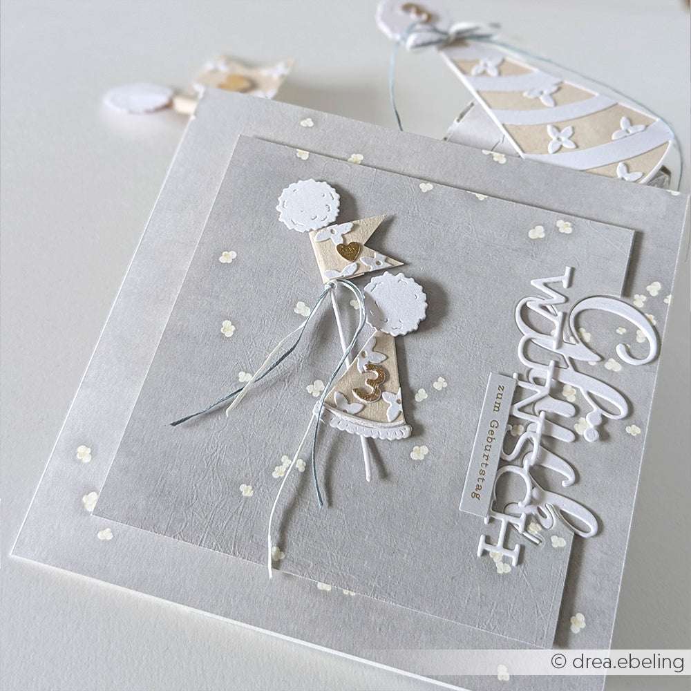 Handgemachte Karte von Alexandra Renke mit einem Engel aus Papier auf strukturiertem Hintergrund, hergestellt mit Deep Edge Motivstanzen und mit "Glückwunsch" in eleganter weißer Schrift.