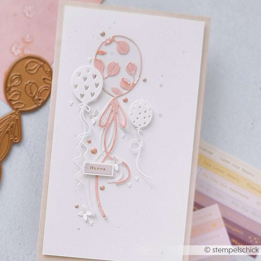 Handgefertigte Karte mit drei pastellfarbenen Luftballons, Herzen und dem Wort Hurra auf weißem Hintergrund, hergestellt mit Motivstanze Luftballons von Alexandra Renke für eine charmante Note.