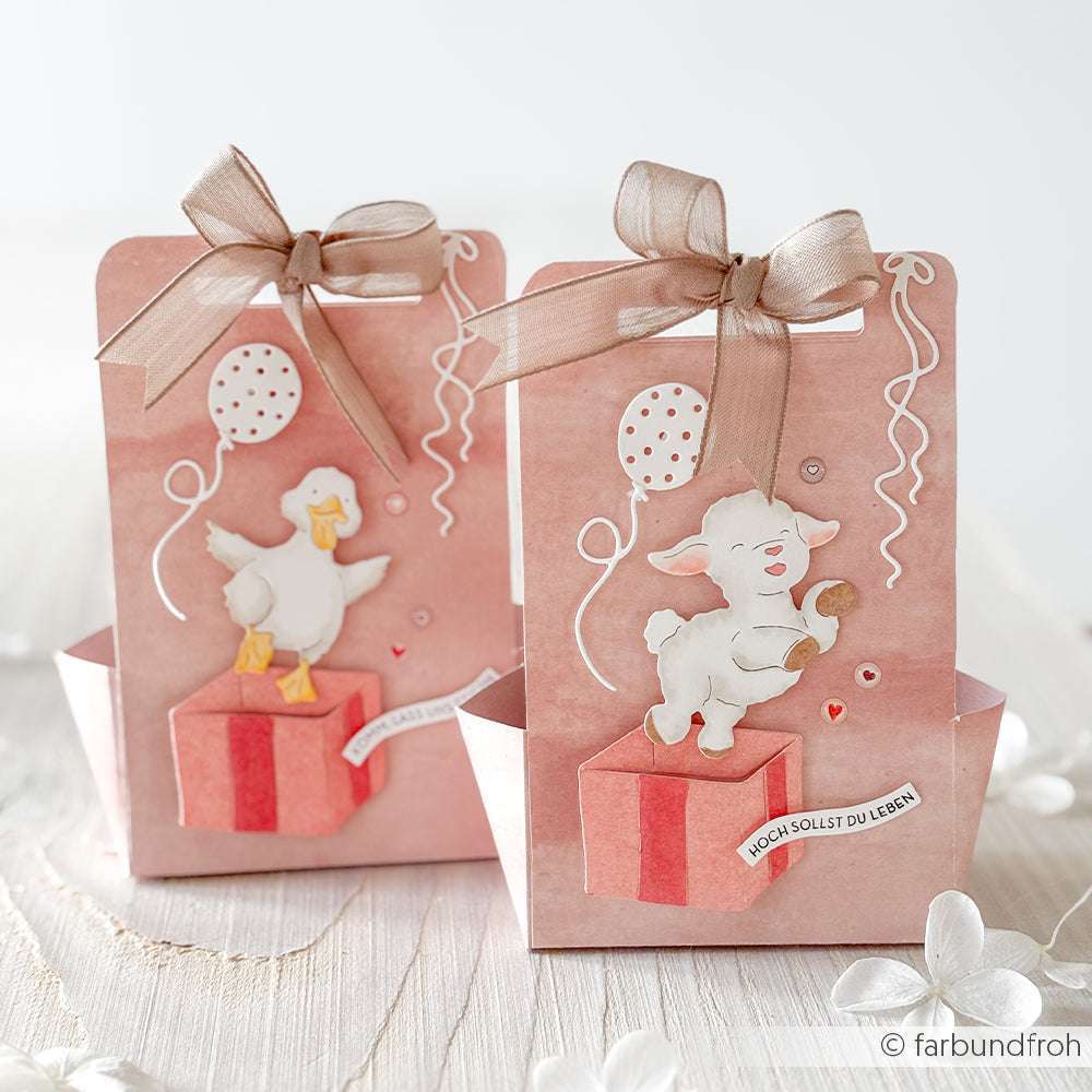 Zwei rosafarbene Geschenktüten mit Tierillustrationen, festlicher Dekoration und Ballons, die mit Alexandra Renkes Deep Edge Motivstanzen und Luftballons gestanzt wurden, ruhen auf hellem Holz - ideal, um Ihre PAPPcut®ies-Kreationen zu präsentieren.
