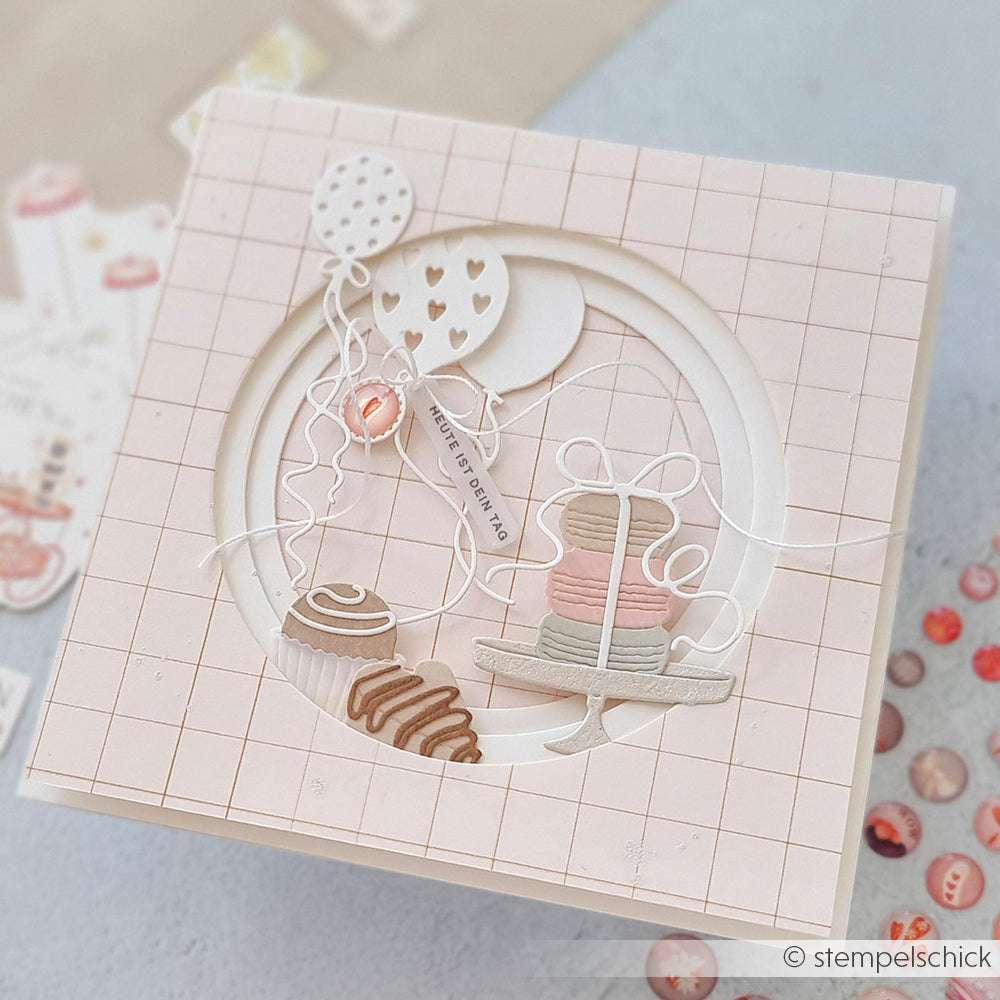 Quadratische Grußkarte von Alexandra Renke mit Luftballons, Gebäck und Kuchen auf einem hellrosa Gitterhintergrund mit charmanten PAPPcuties-Akzenten und dem entzückenden Motivstanze-Macaronstapel-Motiv.