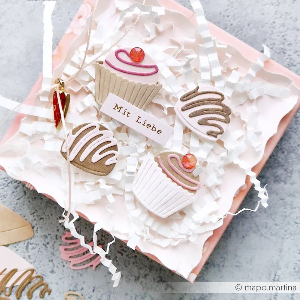 Dekorative Cupcakes und süße Leckereien auf geschreddertem Papier mit einem "Mit Liebe"-Anhänger - perfekt veredelt mit dem PAPPcuties Motivstanze Pralinenset von Alexandra Renke für eine charmante Präsentation.