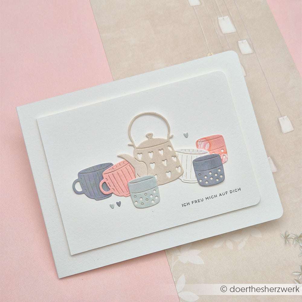 Eine Karte mit einer pastellfarbenen Teekannen- und Tassen-Illustration, die mit dem Alexandra Renke Motivstanze Kleines Teeset hergestellt wurde und den deutschen Text "Ich freu mich auf dich" zeigt.