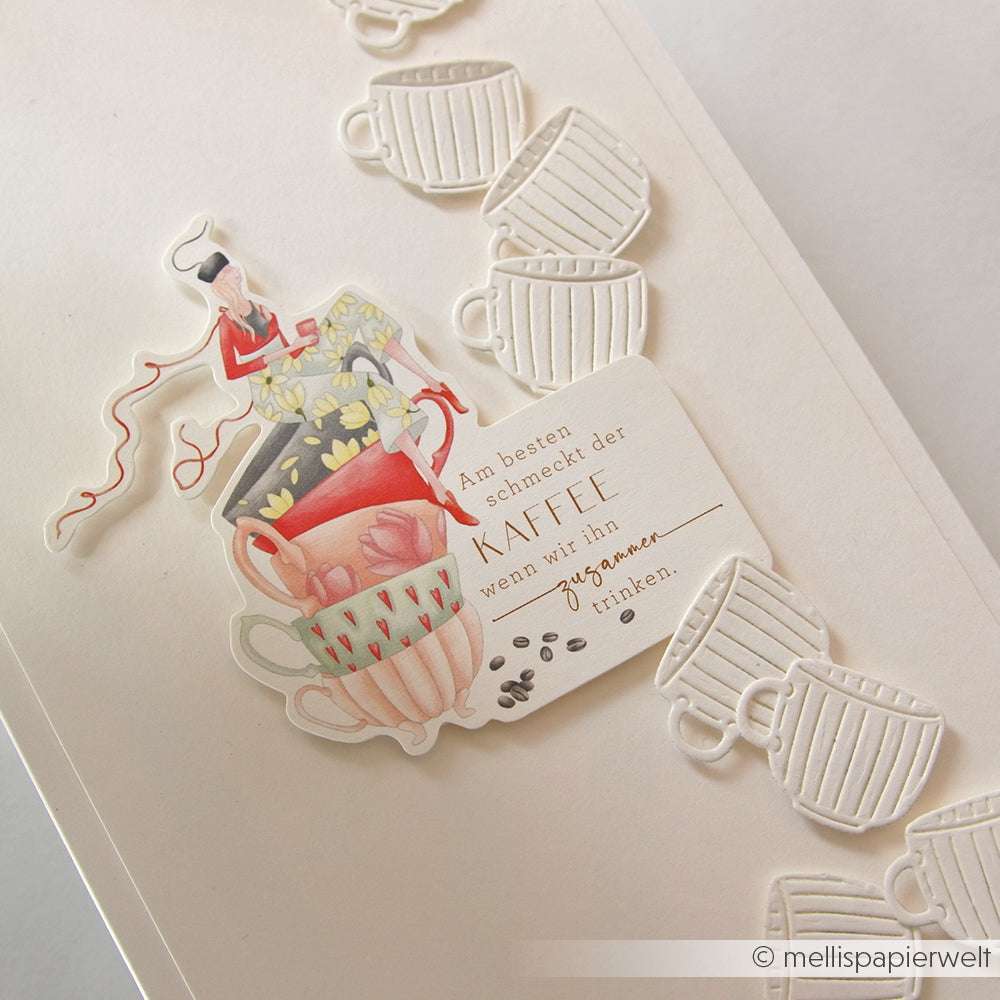 Gestapelte Teetassen-Illustration mit einem deutschen Kaffee-Zitat, hergestellt mit der Alexandra Renke Motivstanze Kleines Teeset, neben geprägten weißen Teetassenmotiven auf einer cremefarbenen Karte.