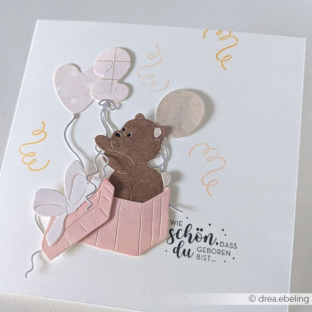 Eine bezaubernde Alexandra Renke PAPPcut®ies Karte mit einem Bären in einer rosafarbenen Box mit Luftballons, deutschem Text und Wirbeln - perfekt für die Kombination mit Deep Edge Motivstanzen oder einer Motivstanze Geschenkbox.