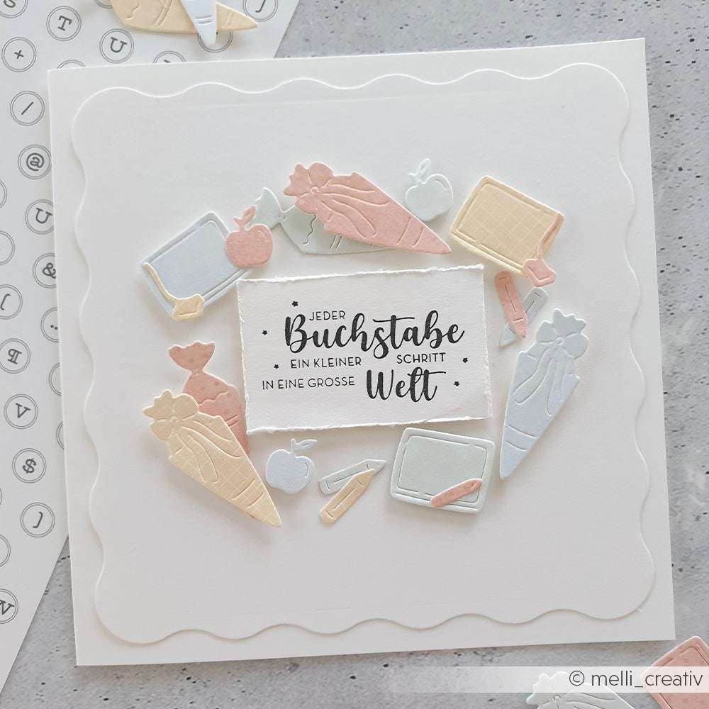 Quadratische Karte mit der Motivstanze Einschulung von Alexandra Renke und PAPPcut®ies, verziert mit pastellfarbenen Schulmotiven und deutschem Text in der Mitte auf weißem Hintergrund.