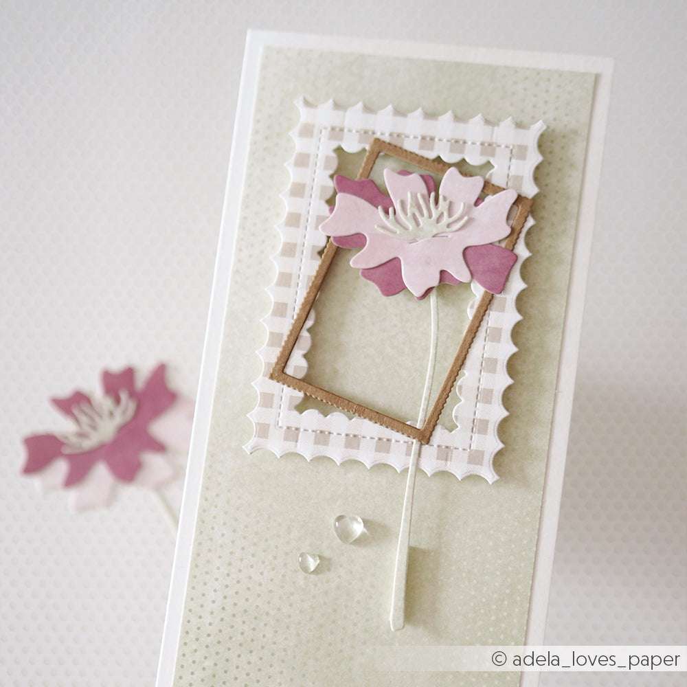 Handgefertigte Karte von Alexandra Renke mit einer geschichteten rosa Blume, weißen Rahmenakzenten, die mit Deep Edge Motivstanzen hergestellt wurden, und zwei klaren Tropfen auf einem sanften grünen Hintergrund.