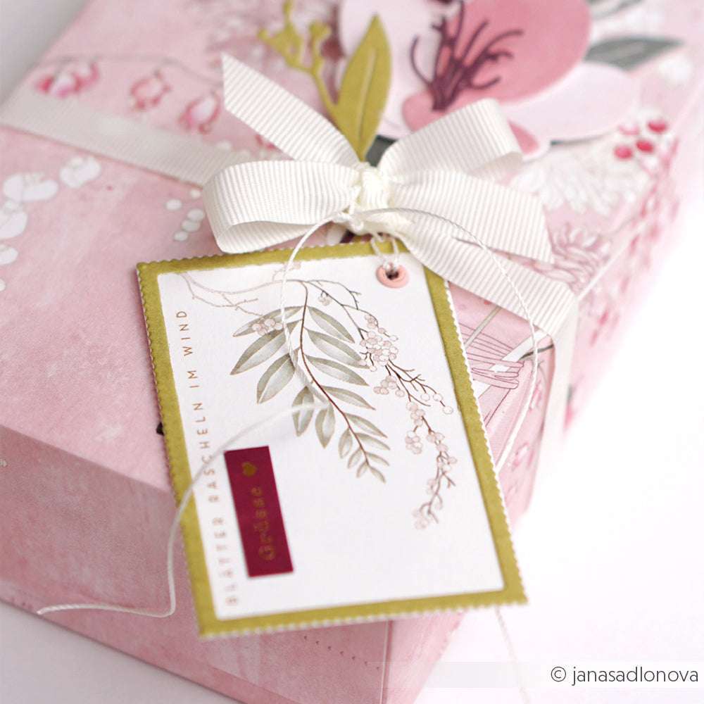 Eine rosafarbene, florale Geschenkbox von Alexandra Renke mit weißem Band und botanischem Geschenkanhänger, gefertigt mit Deep Edge Motivstanzen für atemberaubende Details.