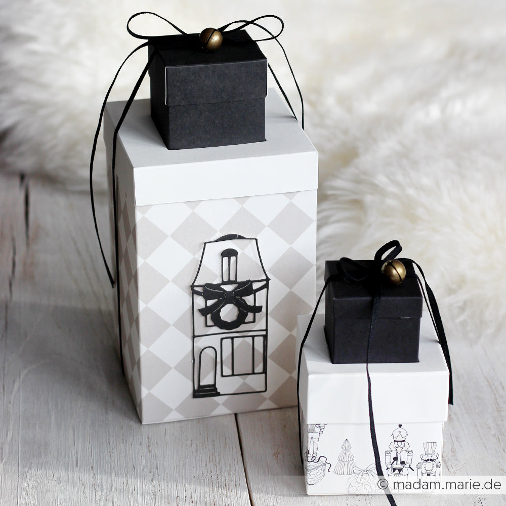 Zwei dekorative Geschenkboxen von Alexandra Renke mit schwarzem Bändchendeckel und minimalistischem schwarz-weißem Gebäudedesign, gefertigt aus hochwertigen Designpapieren und der Motivstanze Großes Haus schmal die.