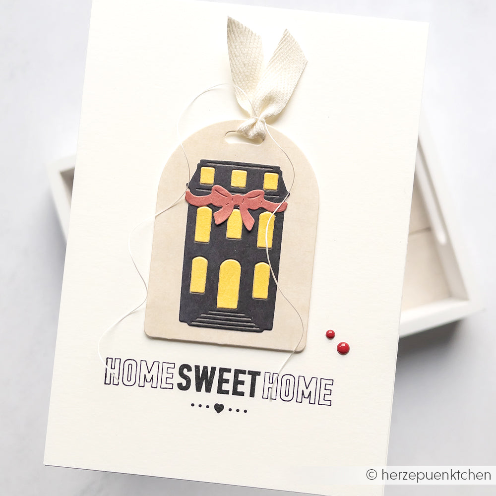 Handgefertigte Karte "Home Sweet Home" von Alexandra Renke, gestaltet mit Designpapier, einem Hausanhänger aus der Schleifenhaus-Stanze, Schleifenband und zwei roten Deko-Punkten.