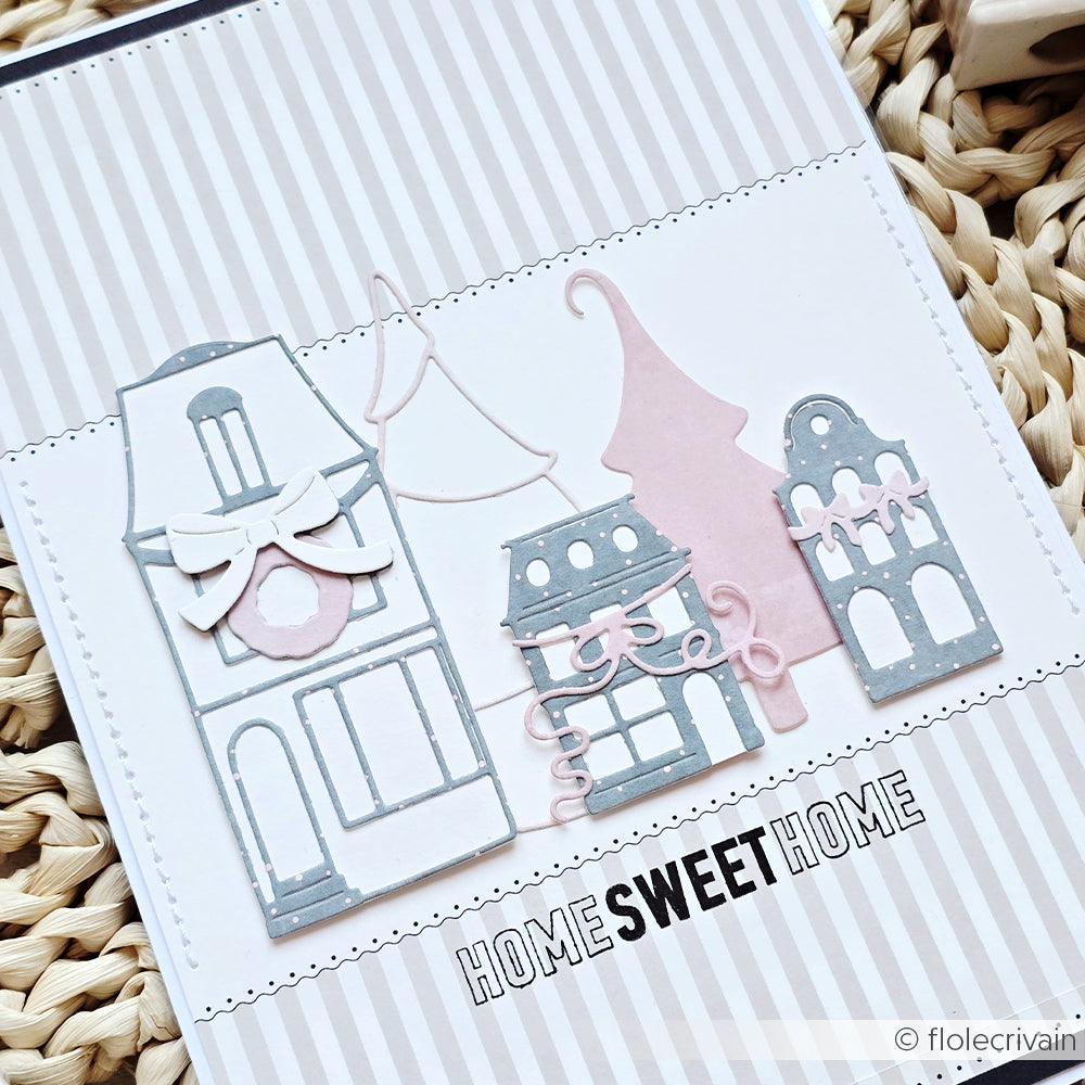 Handgemachte Karte von Alexandra Renke mit pastellfarbenen Häusern, die mit Motivstanze und DieCut Systemen ausgeschnitten wurden, mit dem Text "HOME SWEET HOME" auf einem gestreiften Designpapiere-Hintergrund.