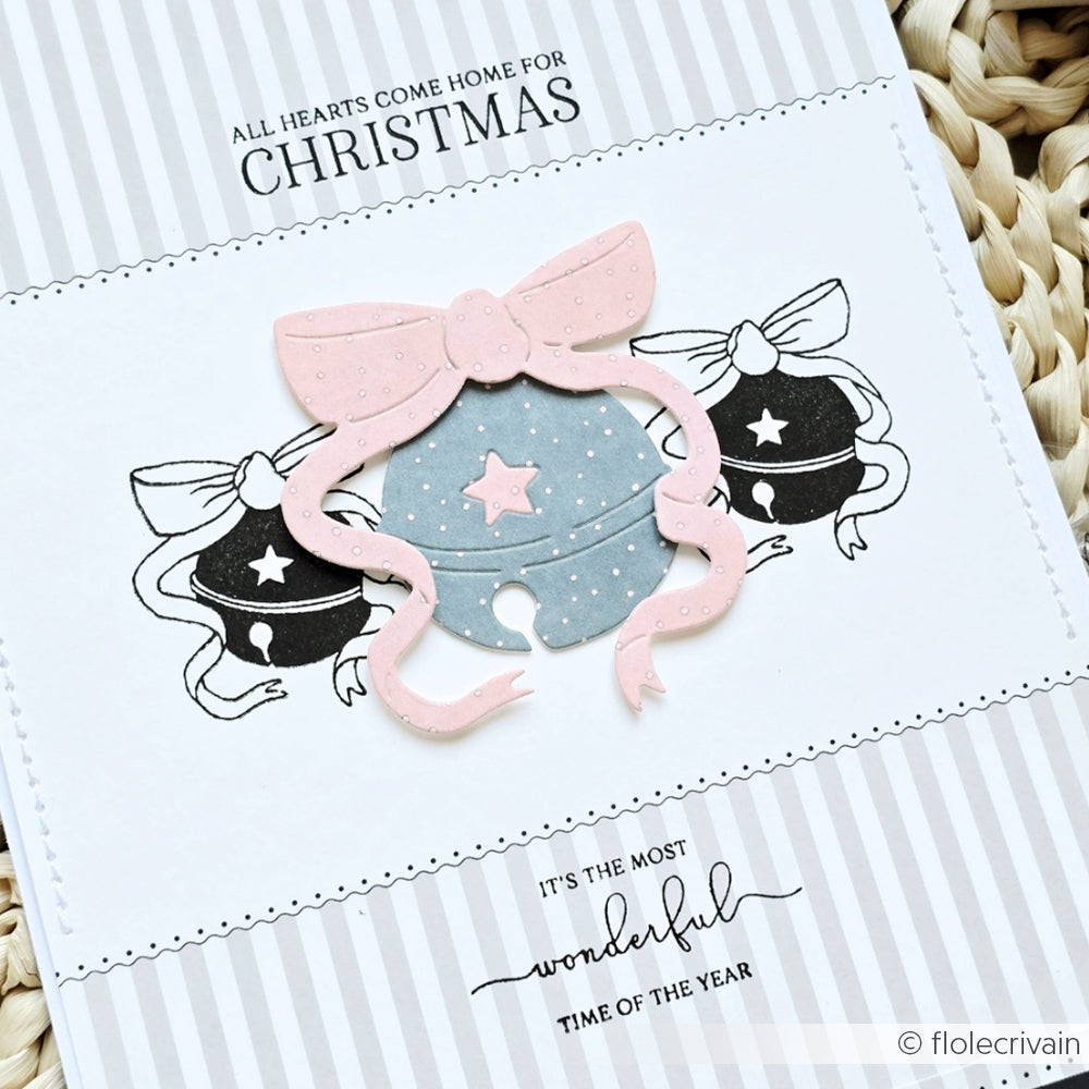 Handgefertigte Weihnachtskarte aus Alexandra Renke Designpapier, verziert mit der Motivstanze Fröhliche Sternenglocke, mit Glöckchen, rosa Schleife und dem Text "All hearts come home for Christmas".