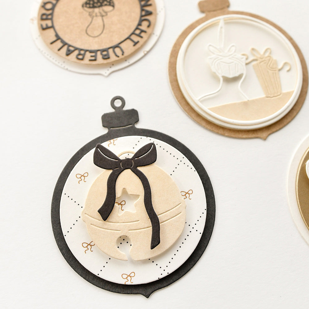 Die handgefertigten Papierornamente von Alexandra Renke zeichnen sich durch mehrschichtige Designs und Schleifen in neutralen Tönen auf weißem Hintergrund aus.