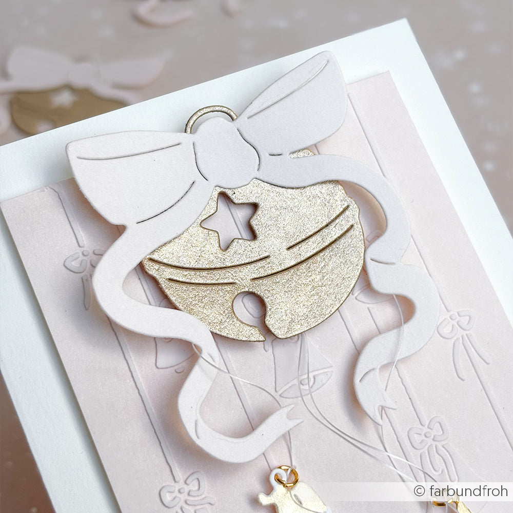 Eine handgefertigte Karte von Alexandra Renke, verziert mit einer goldenen Jingle Bell und einer großen weißen Schleife, hergestellt mit Dies und der Motivstanze Fröhliche Sternenglocke für festlichen Charme.