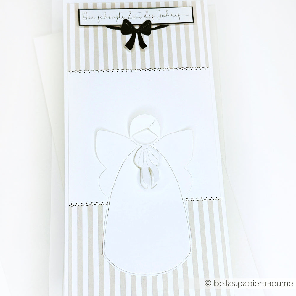 Handgefertigte Karte mit einem weißen Papierengel aus der Alexandra Renke Motivstanze großer ruhiger Engel und einer schwarzen Schleife, auf gestreiftem beige-weißem Designpapier.