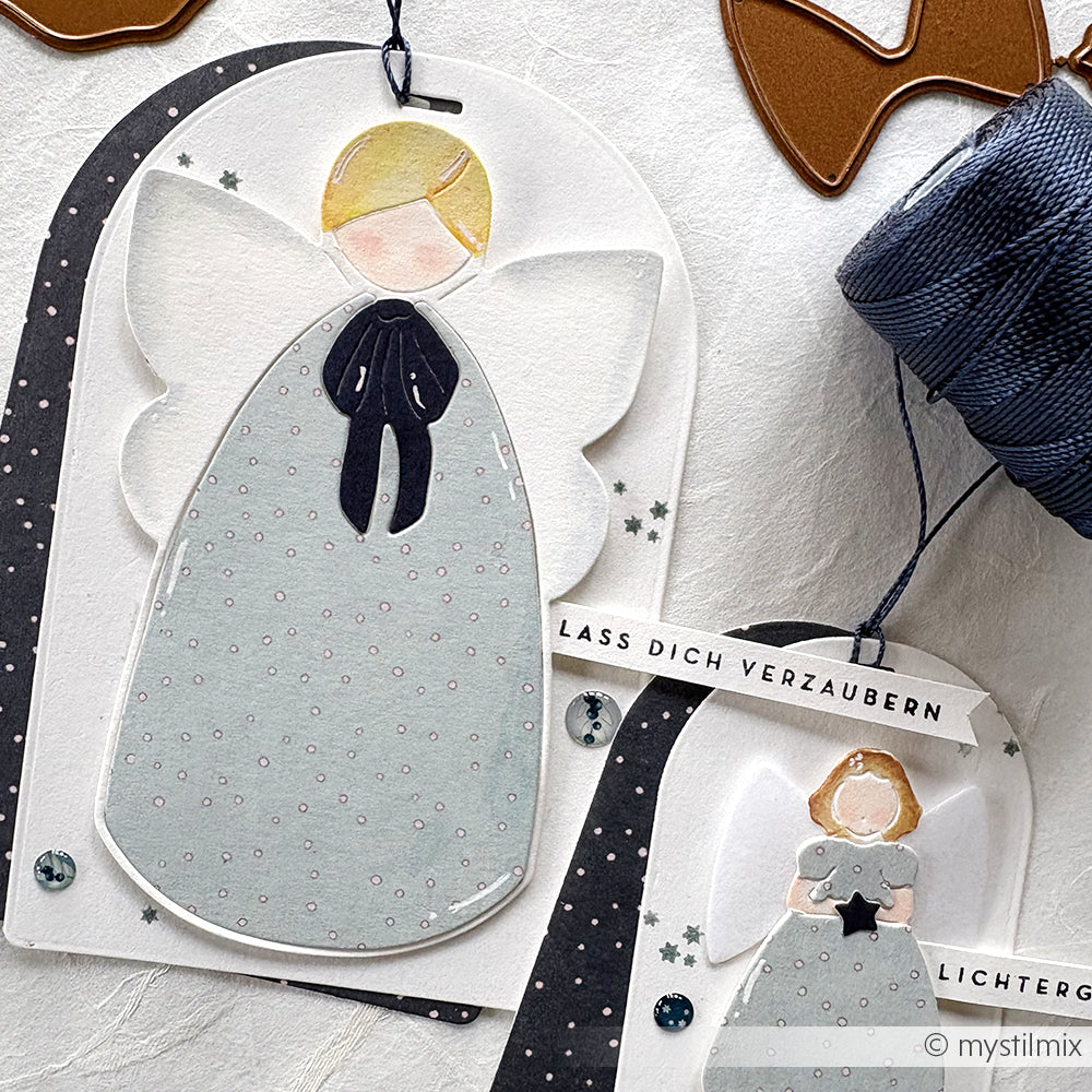 Handgefertigte Engel-Geschenkanhänger mit Pastellfarben, Bändern und dem deutschen Text "Lass dich verzaubern", hergestellt mit der Alexandra Renke Motivstanze Großer ruhiger Engel Die für eine einzigartige, zauberhafte Note.