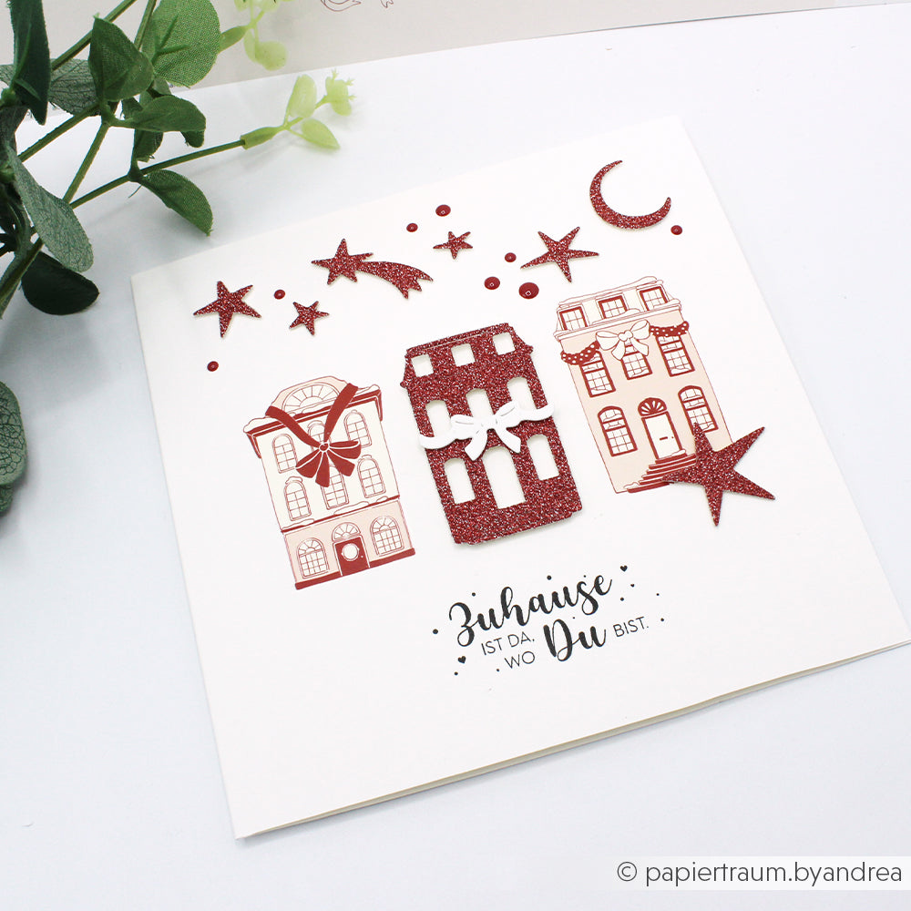 Grußkarte von Alexandra Renke mit drei Häusern, roten Glitzersternen und Mond aus dem Motivstanze Nachthimmel-Set und deutschem Text: Zuhause ist da, wo Du bist.