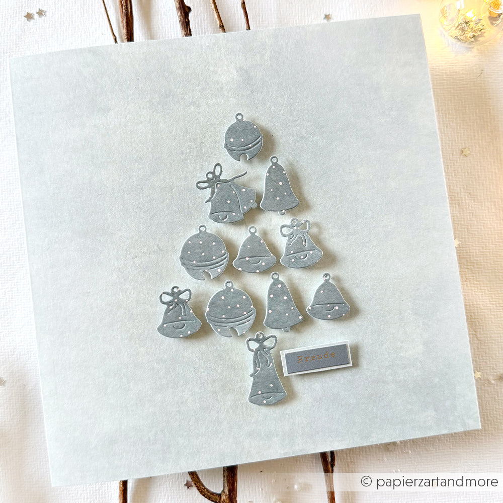Silberne Glöckchen aus der Alexandra Renke Motivstanze Glöckchen sind in Form eines Weihnachtsbaums auf einer quadratischen weißen Karte mit dem Schriftzug Freude" am unteren Rand angeordnet.