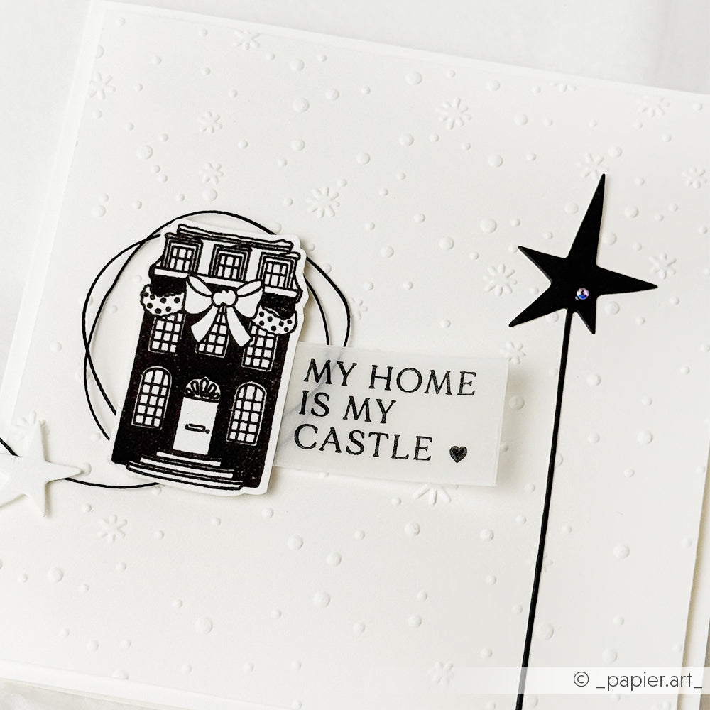 Eine handgefertigte Karte von Alexandra Renke zeigt eine schwarze Hausillustration und den Text MY HOME IS MY CASTLE" auf weißem, gepunktetem Designpapier, akzentuiert mit zarten sternförmigen Motivstanze Sternen.