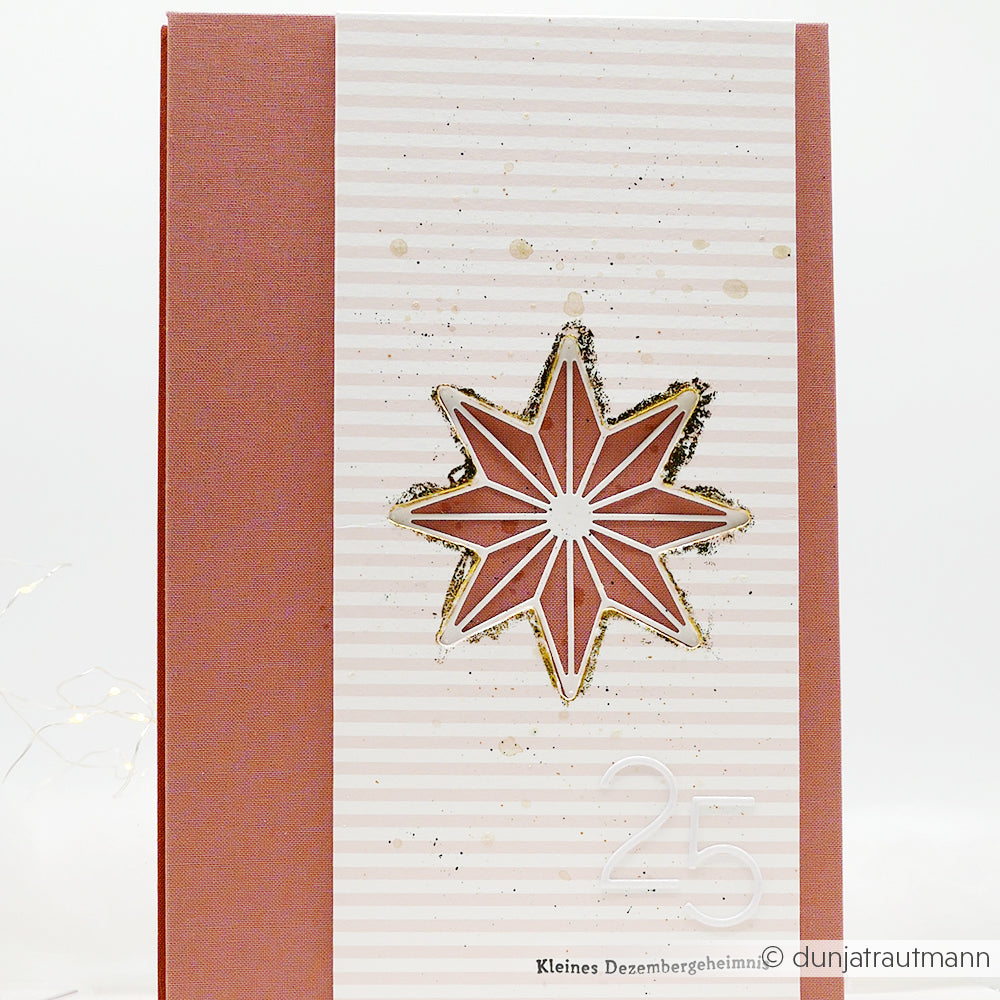 Die rosa-weiße Karte von Alexandra Renke aus hochwertigen Designpapieren zeigt einen goldverzierten Stern mit der Motivstanze Achterstern und der Zahl 25 in der rechten unteren Ecke.