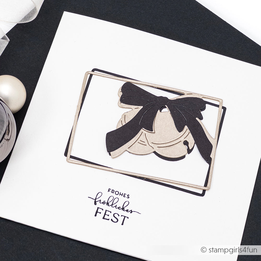 Eine handgefertigte Weihnachtskarte von Alexandra Renke, hergestellt mit Motivstanze und eleganten Designpapieren, zeigt eine schwarze Schleife, Glocken und den deutschen Text "Frohes Fest" auf weißem Hintergrund.