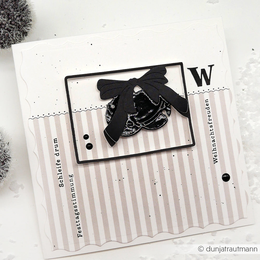 Handgemachte Weihnachtskarte von Alexandra Renke mit schwarzen Schleifen, Glöckchen und dem Buchstaben W auf gestreiften Designpapieren mit festlichen Grüßen.