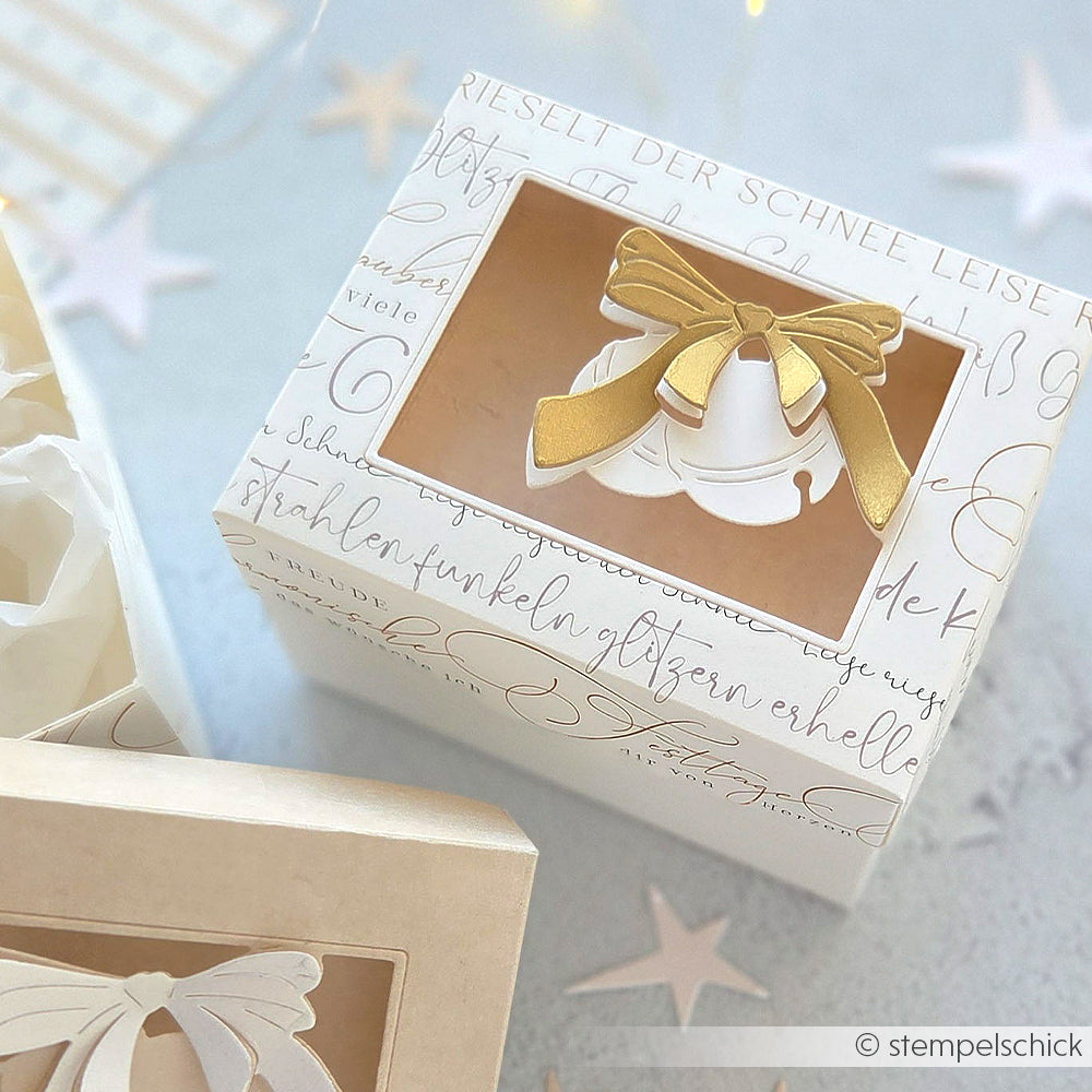 Weiße Geschenkschachtel von Alexandra Renke mit goldenem Band und Glocke, sichtbar durch ein Klarsichtfenster - perfekt für die Präsentation von Geschenken mit Motivstanze oder eleganten Designpapieren.