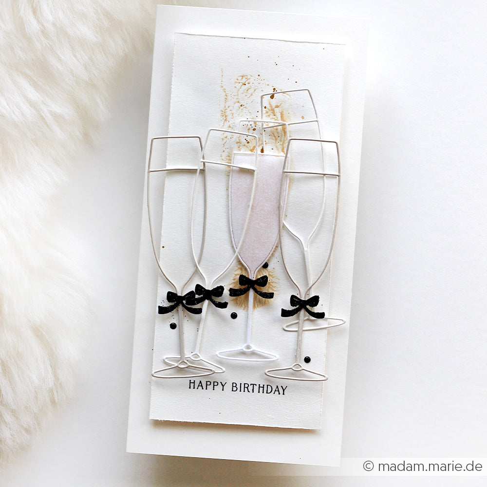 Handgefertigte Geburtstagskarte von Alexandra Renke mit fünf Motivstanze Sektgläsern, schwarzen Schleifen und dem Text "Happy Birthday" am unteren Rand. Gefertigt mit hochwertigen Designpapieren für einen stilvollen, festlichen Look.