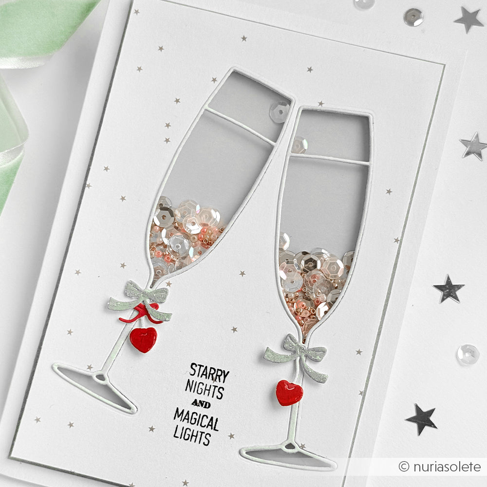 Grußkarte mit zwei Sektgläsern, die mit der Stanze Großes Outline Sektglas von Alexandra Renke ausgestanzt wurden, gefüllt mit Pailletten und roten Herzanhängern, sowie der Botschaft STARRY NIGHTS AND MAGICAL LIGHTS. Ideal für Fans des Stanzens.