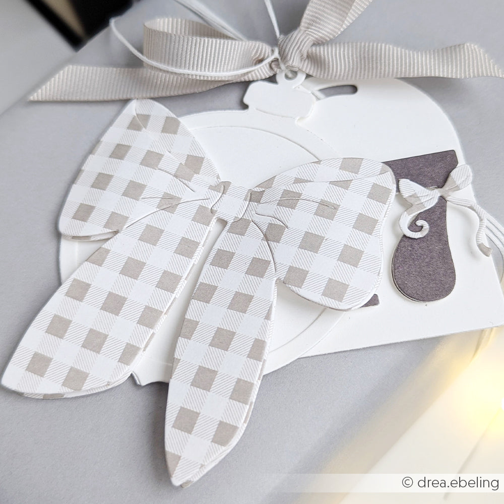 Geschenkanhänger von Alexandra Renke mit grau-weiß karierter Prachtschleife und Schleife, befestigt mit einem grauen Band - fachmännisch gefertigt mit präzisen Stanzsystemen für einen eleganten Schliff.