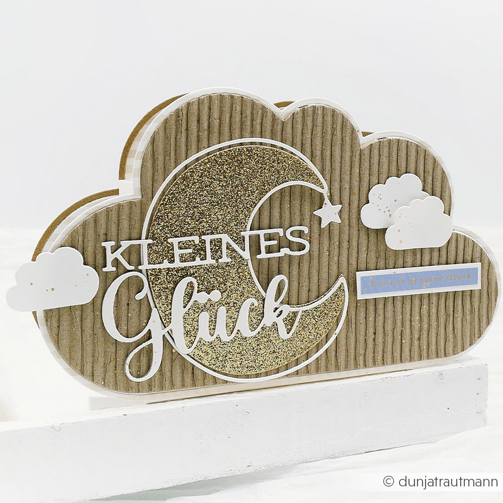 Wolkenförmige Karte von Alexandra Renke aus hochwertigem Papier, verziert mit einer glitzernden Mondsichel, Sternen und dem Schriftzug "Kleines Glück" - veredelt mit den Motivstanze Traumkonfetti Dies.
