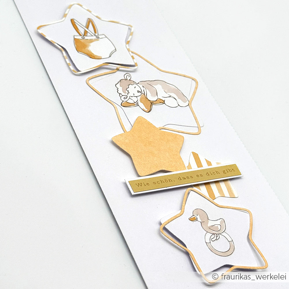 Weiße Karte von Alexandra Renke aus hochwertigem Designpapier mit Sternausschnitten aus der 5 Sternrahmen-Stanze, Baby-Illustrationen und deutschem Text: "Wie schön, dass es dich gibt.