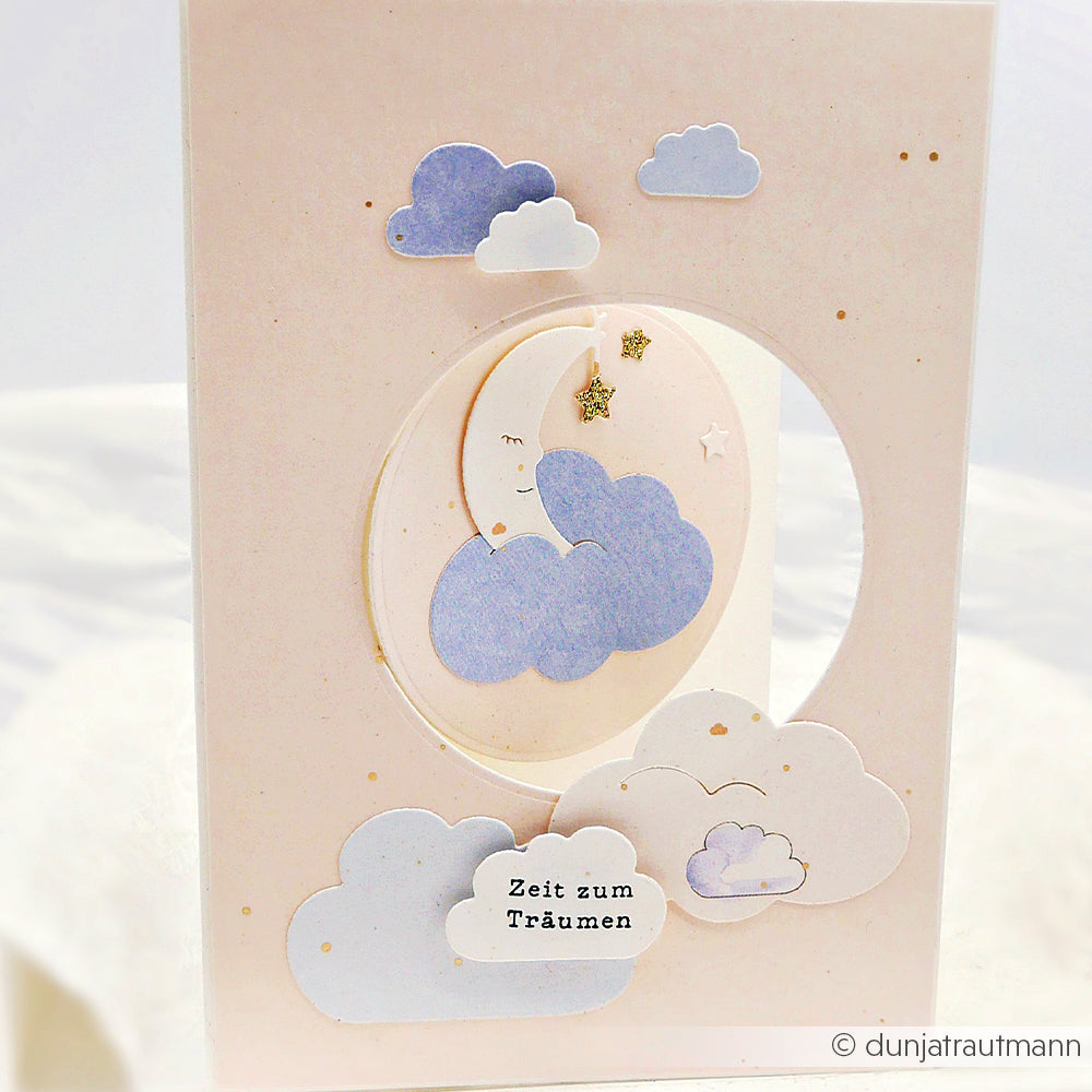 Die Grußkarte von Alexandra Renke zeigt zarte Pastellwolken, eine Mondsichel und den Text "Zeit zum Träumen", verziert mit Akzenten von Motivstanze Dies und hochwertigem Designpapier für eine zarte Note.