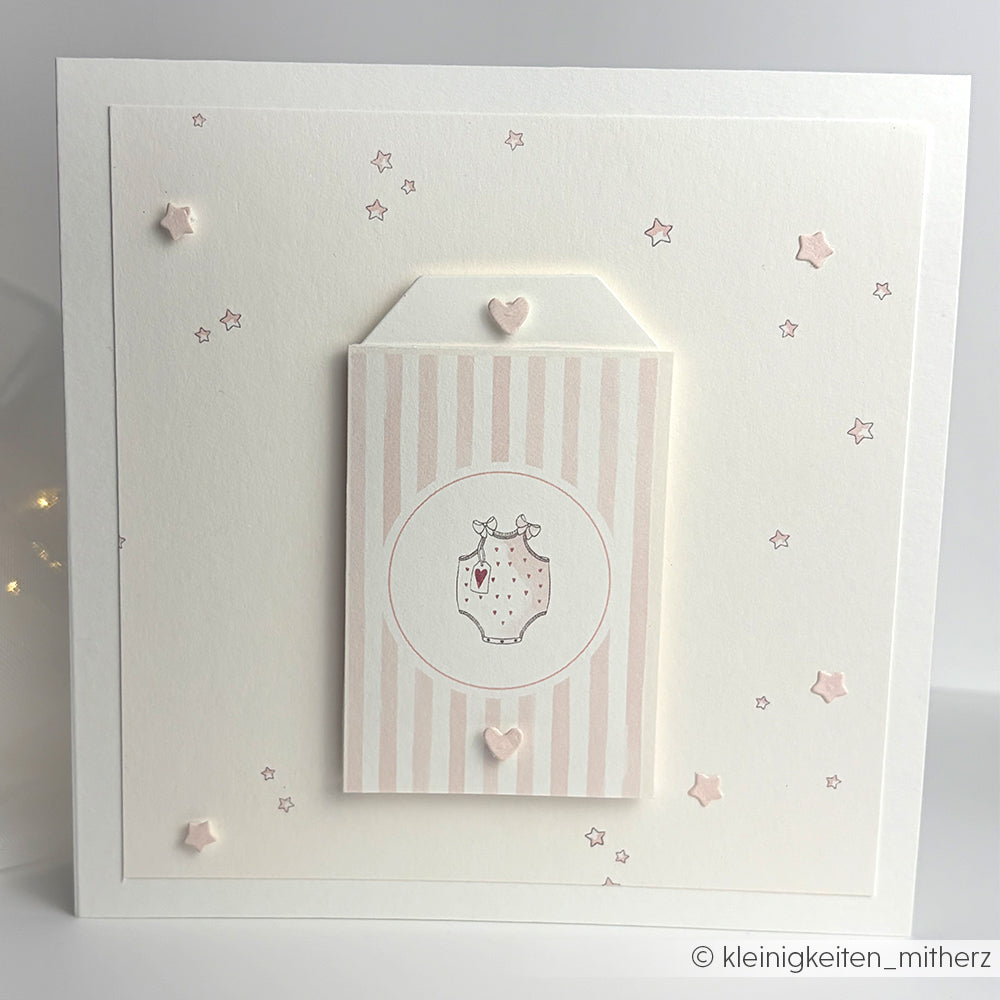 Quadratische Grußkarte von Alexandra Renke aus Designpapier mit einem rosa gestreiften Glas, kleinen Sternen und einer Herz-Etikettenstanze auf einem sauberen weißen Hintergrund.