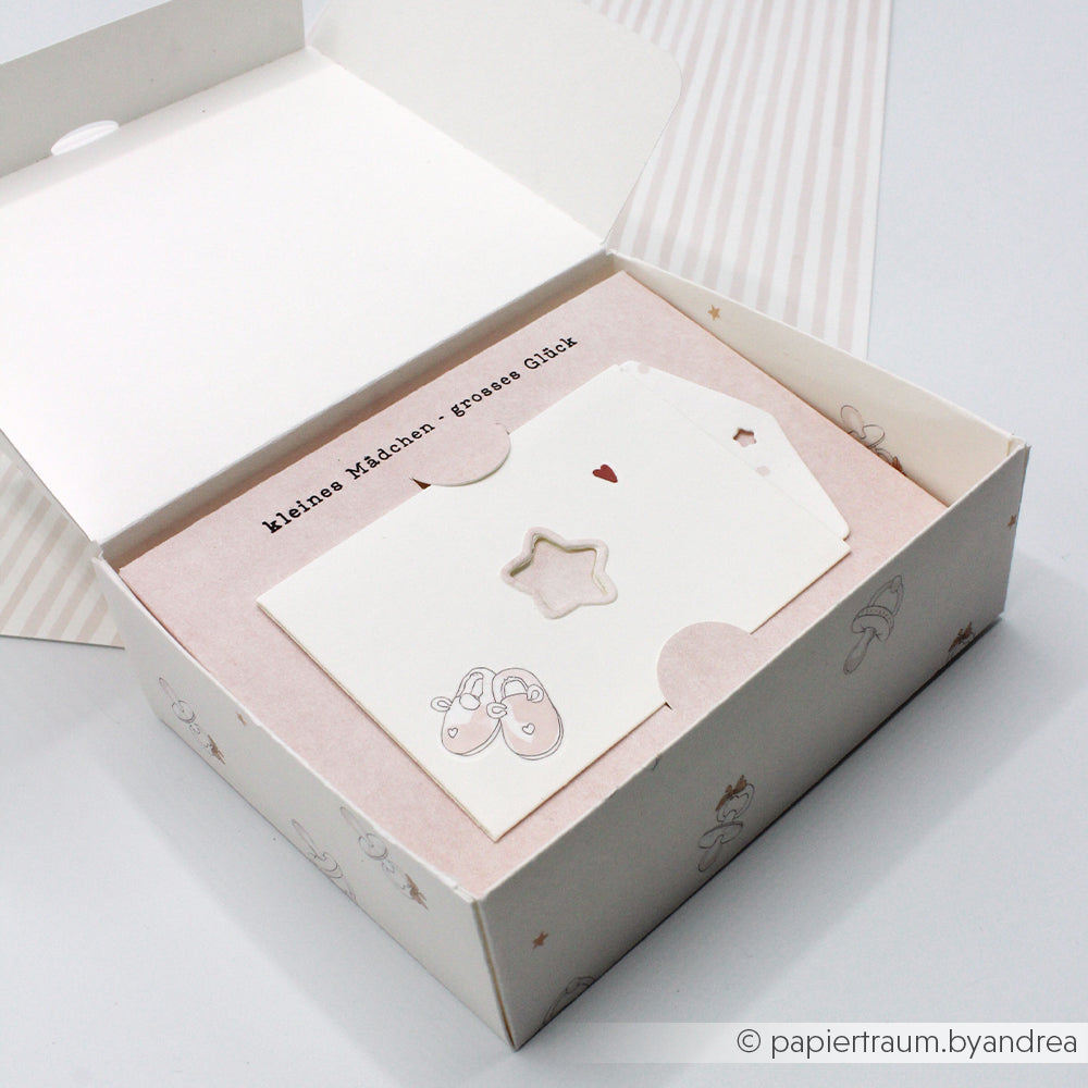 Geschenkkarton mit Babykarten von Alexandra Renke, darunter eine Karte mit einem Etikett im Tütchen-Stern und eine weitere mit einem rosa Babyschuh aus einer Motivstanze.