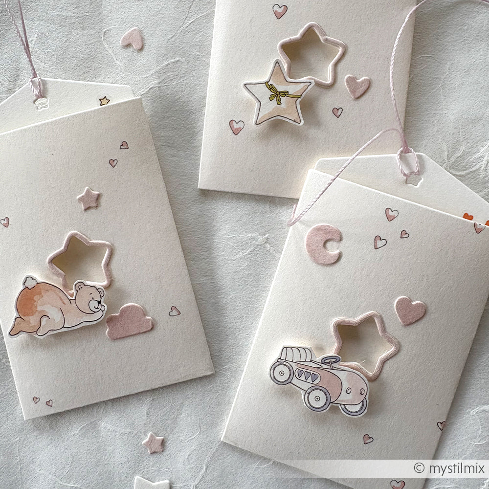 Die drei pastellfarbenen Geschenkanhänger von Alexandra Renke sind mit sternförmigen DieCut Systeme Ausschnitten versehen und mit Herzen, einem Bären und einer Autoillustration verziert.