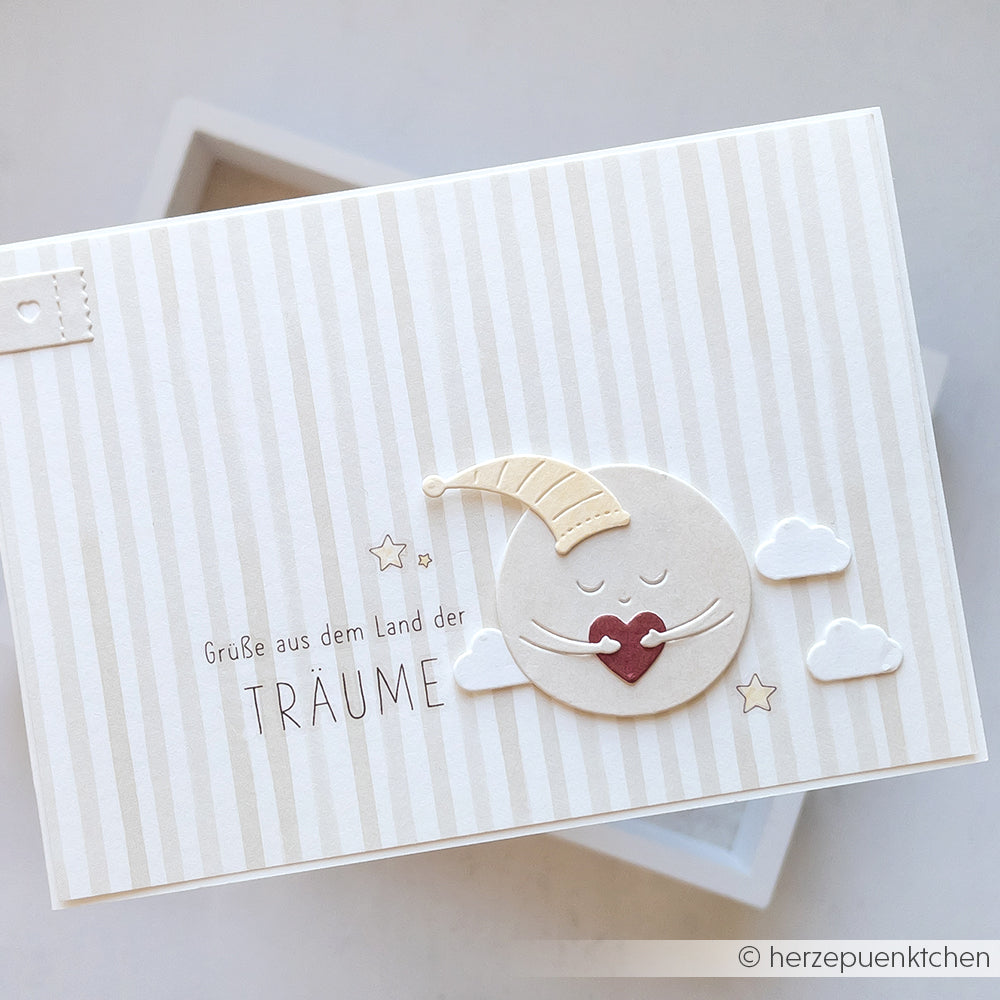 Grußkarte mit einem lächelnden Mond in einer Nachtmütze, Wolken, Sternen und deutschem Text auf Streifen - gestaltet mit Alexandra Renke Designpapieren und einer verspielten Motivstanze für einzigartige Akzente.