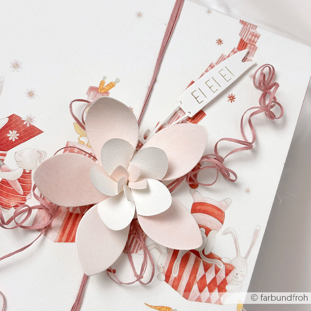 Geschenkverpackung mit Alexandra Renke Designpapieren, einer rosafarbenen Papierblume, rosafarbener Kordel und einem weißen EI EI EI Anhänger auf festlichem Tierprint. Verwenden Sie Ihre Motivstanze Freundliche Fähnchen für zusätzlichen Charme!.