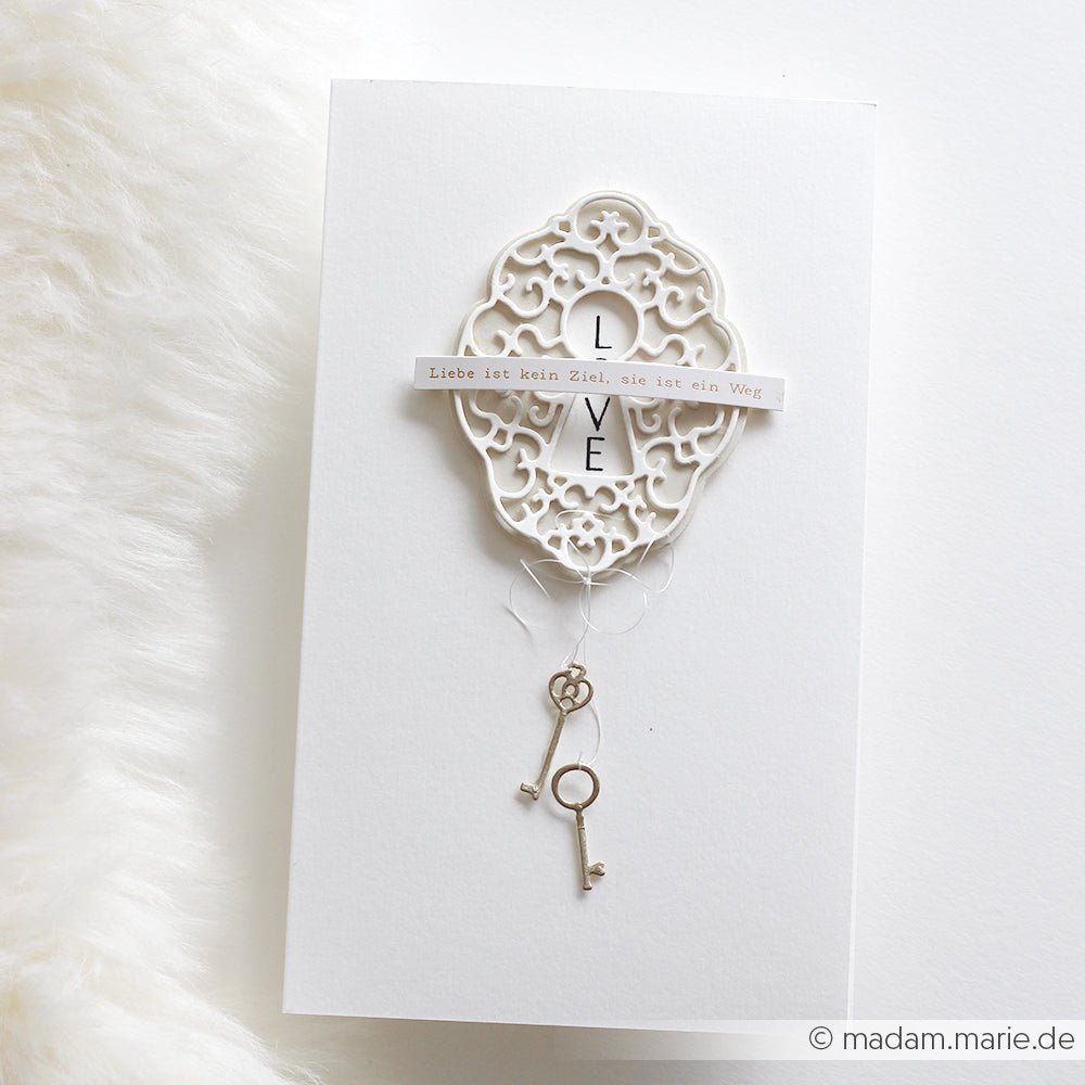 Elegante Karte von Alexandra Renke mit filigranem Schlüsselloch-Ornament, LOVE-Text, deutschem Spruch, zwei kleinen Hängeschlüsseln und gefertigt aus hochwertigem 200g Designpapier.