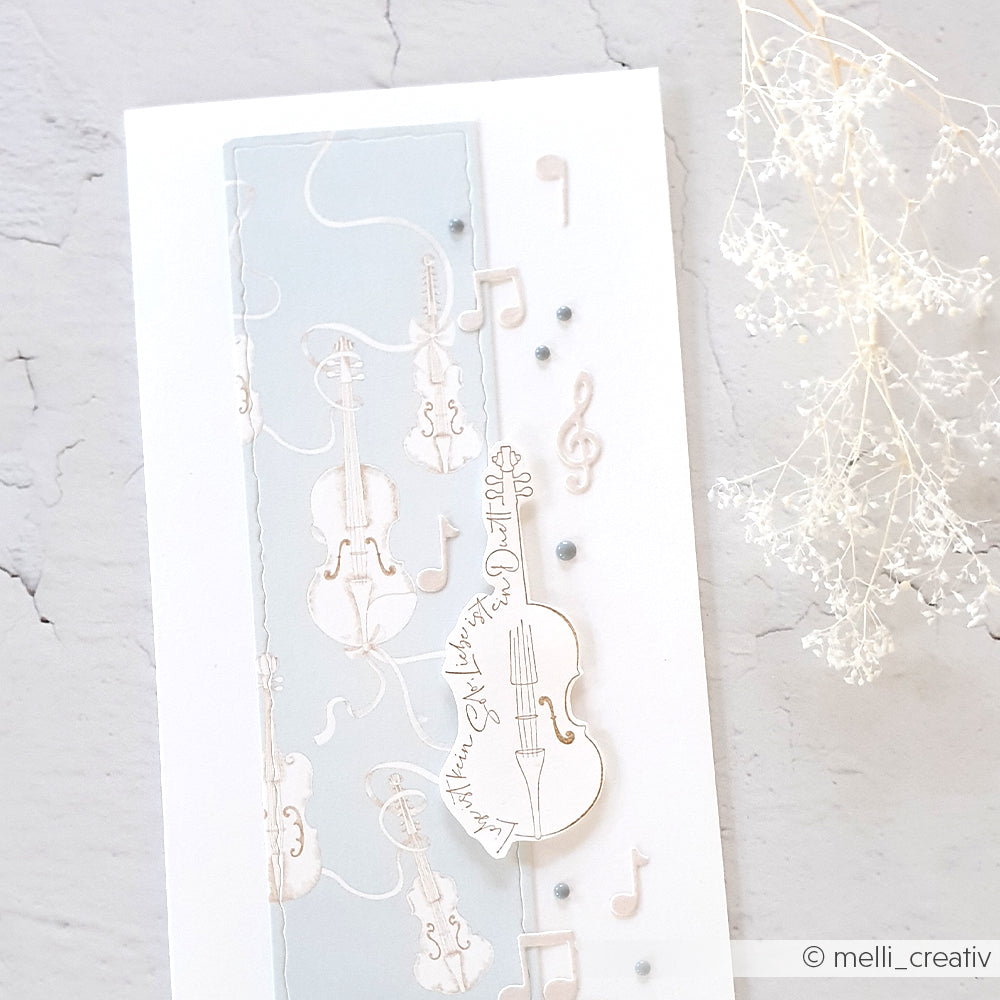 Handgefertigte Karte mit weißer und blauer Violine, Noten und Violinschlüssel auf strukturiertem weißen Hintergrund, hergestellt mit Alexandra Renke Motivstanze Noten Anhänger und hochwertigen Designpapieren.