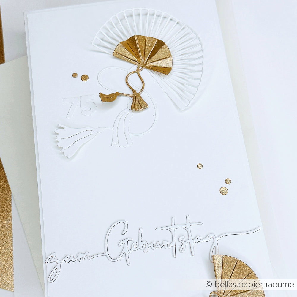 Die elegante weiß-goldene Geburtstagskarte von Alexandra Renke zeigt einen Fächer aus der Motivstanze Großer Fächer, eine Quaste, die Zahl 75 und "zum Geburtstag" in Schreibschrift am unteren Rand.