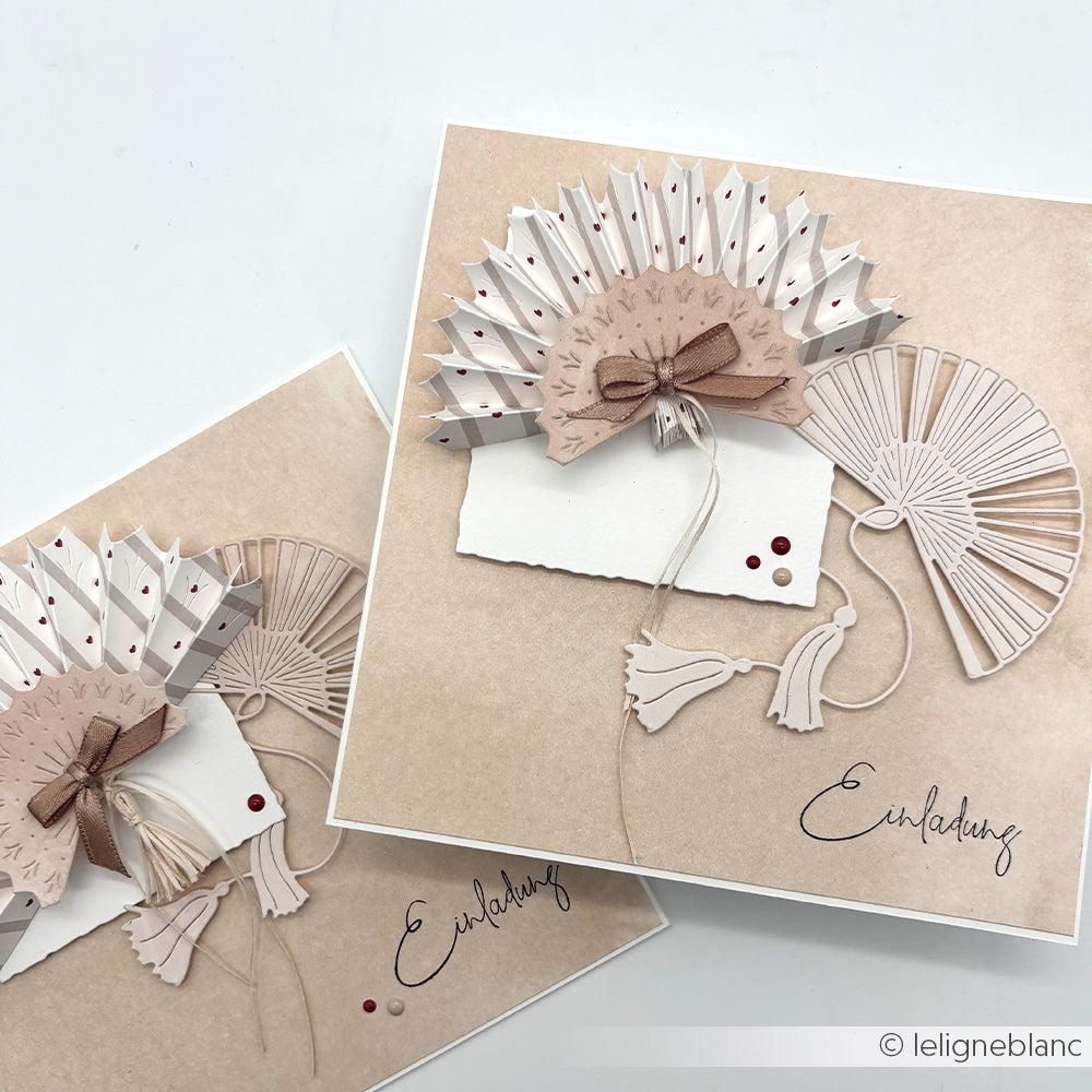 Zwei elegante Einladungskarten aus der Motivstanze Großer Fächer von Alexandra Renke und hochwertigen Designpapieren, verziert mit 3D-Papierfächern, beigen Quasten und Schleifen und mit der Aufschrift "Einladung".