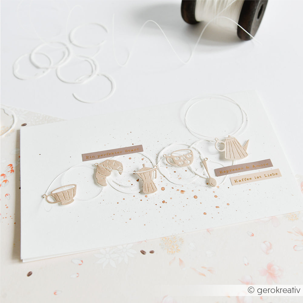 Handgefertigte Karte von Alexandra Renke mit kleinen Kaffee-Ausschnitten, Garn und deutschem Text auf weißem Hintergrund. Hergestellt aus Designpapieren und mit der Stanzform „Genussmoment Anhänger“ unter Verwendung hochwertiger Stanzsysteme.