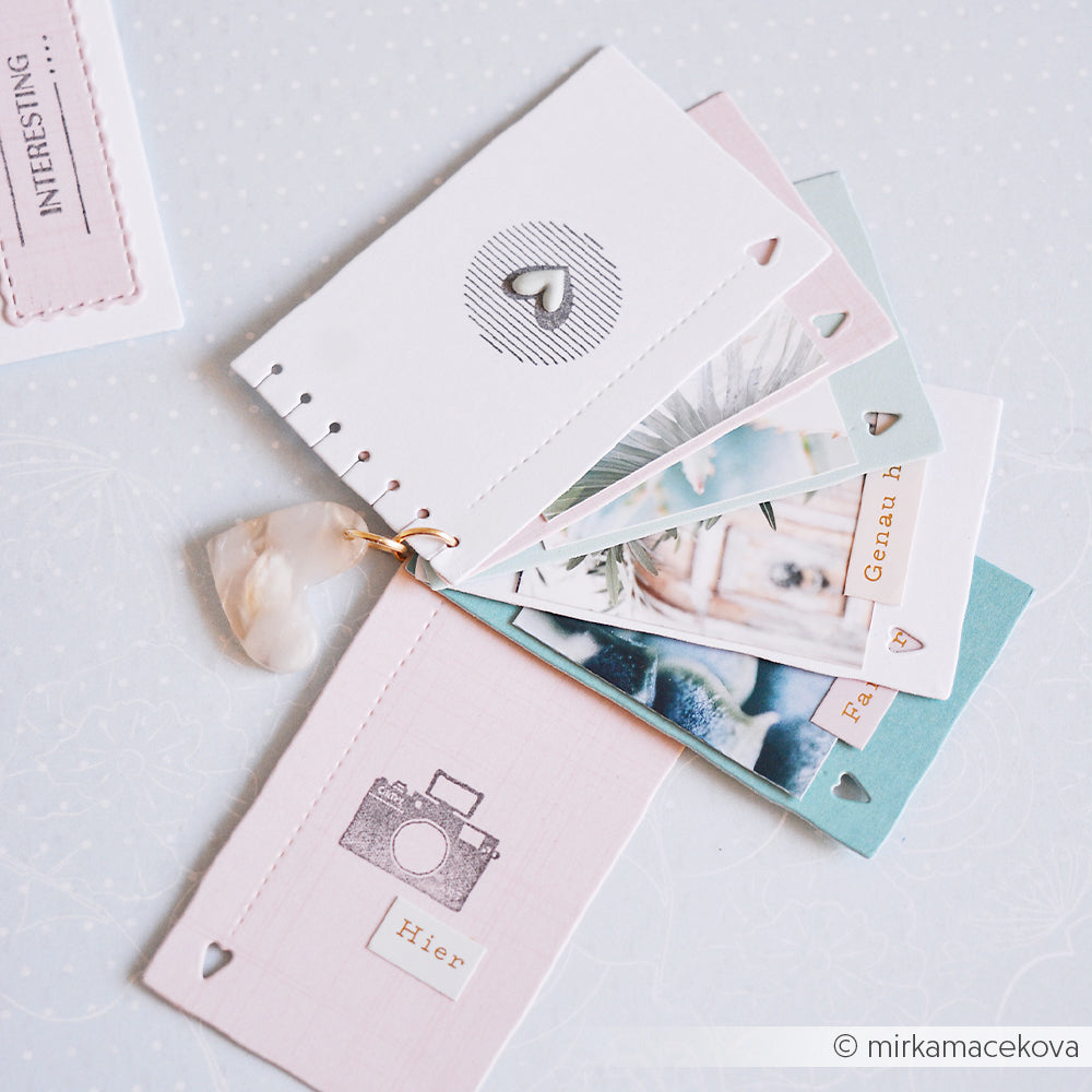 Ein Set pastellfarbener Karten von Alexandra Renke mit Fotos und Herzen, mit einem Ring gebunden und mit einem durchscheinenden Anhänger verziert – jede Karte ist sorgfältig aus bezaubernden Designpapieren gefertigt, wodurch sich diese Kollektion ideal zum kreativen Notieren und Dekorieren eignet.
