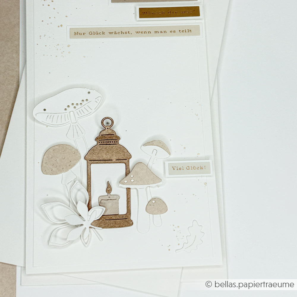 Handgefertigte Karte mit einer Laterne, Pilzen, einer Blume und deutschen Texten, die mit der Motivstanze „Kürbis Gemütlichkeit“ gestaltet wurde und so einen besonderen Charme versprüht. Die in neutralen Farbtönen auf weißem Hintergrund gestaltete Karte bringt hochwertige Designpapiere und filigrane Details wunderschön zur Geltung.