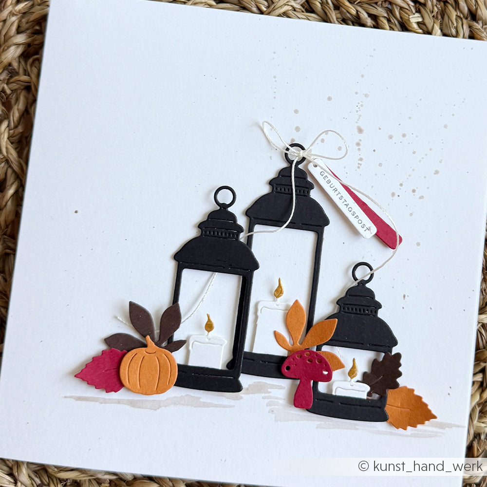 Drei schwarze Laternen, Kerzen, Herbstblätter, ein Kürbis aus der Motivstanze „Kürbis“ und ein roter Pilz auf einer weißen Hintergrundkarte.