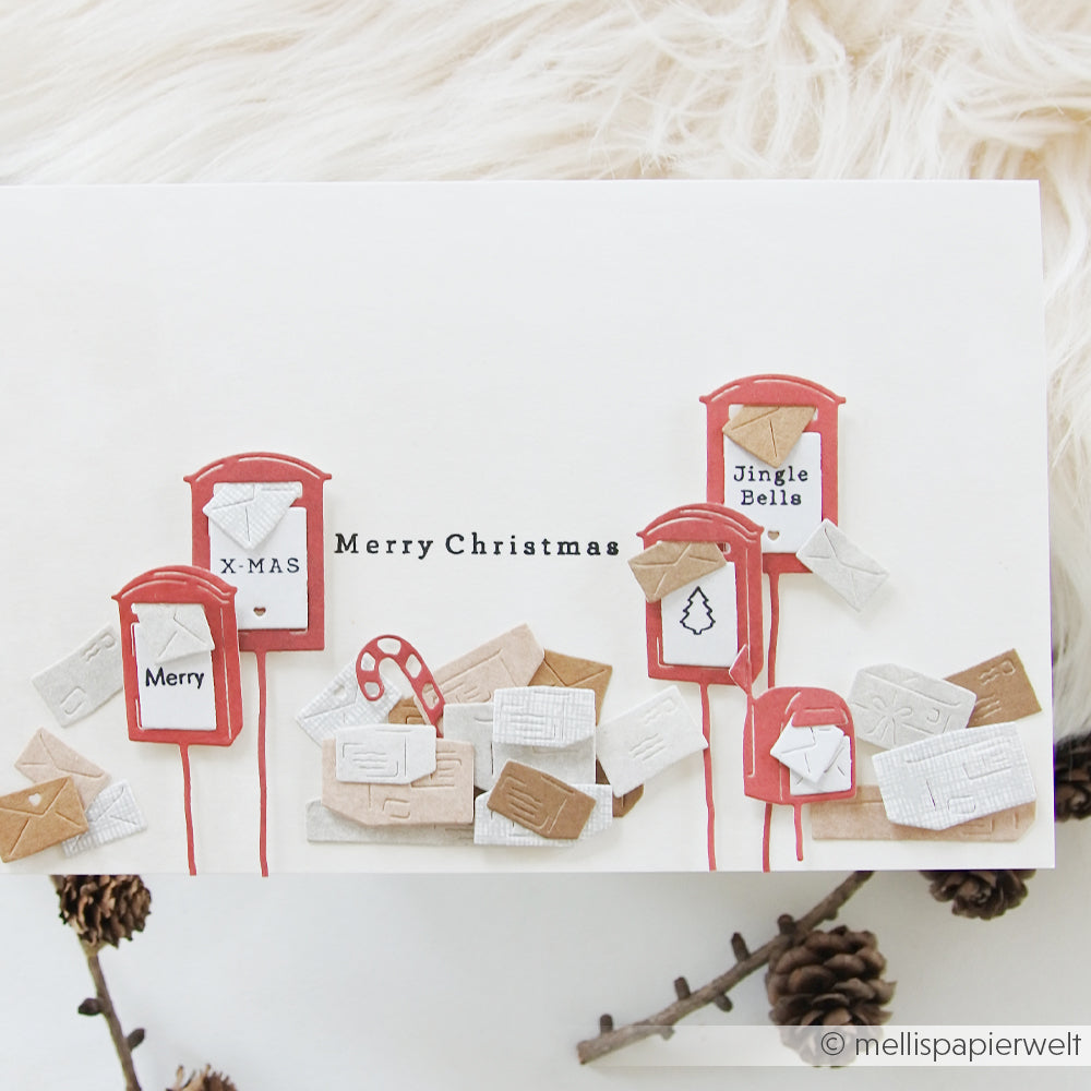 Handgefertigte Weihnachtskarte mit gestanzten Miniatur-Briefkästen, Umschlägen und dem Schriftzug „Merry Christmas“.